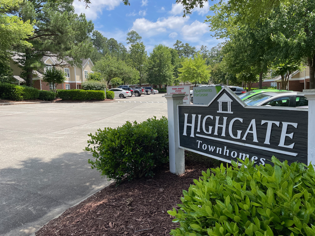 Highgate Entrance A sign that reads Highgate Townhomes in front of a parking lot.
