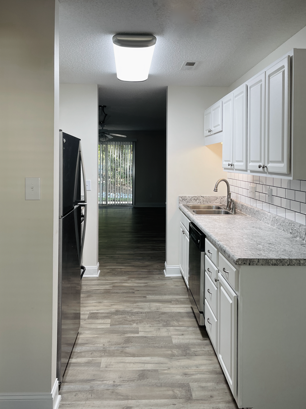 A kitchen with white cabinets and a black refrigerator.