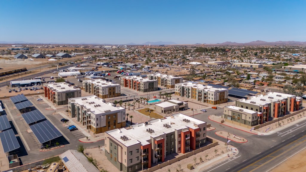 A large, modern housing complex with solar panels on the roofs.