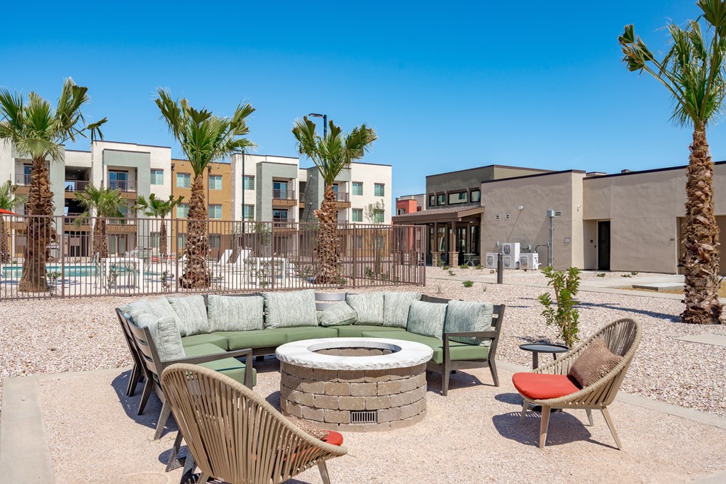 A patio with a fire pit and chairs.
