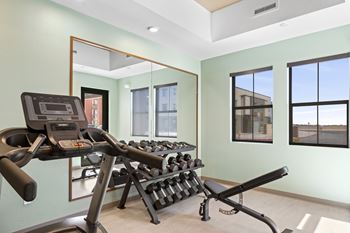 A gym room with a treadmill, weights, and mirrors.