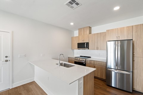 A modern kitchen with a stainless steel refrigerator and wooden cabinets.