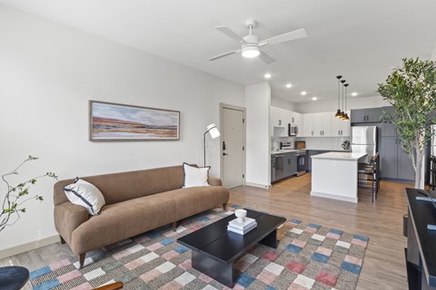 A living room with a brown couch and a ceiling fan.