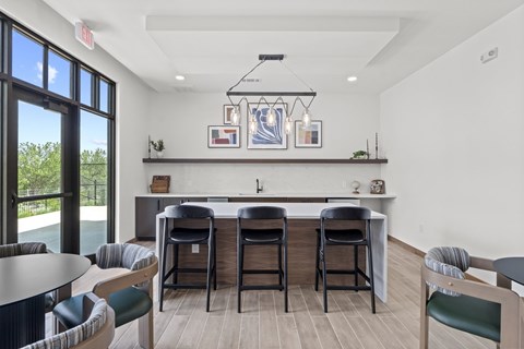 A kitchen with a bar area and chairs around it.