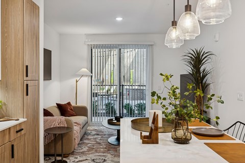 A modern living room with a white dining table and a brown sofa.