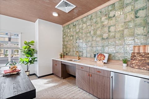 A kitchen with a green tiled backsplash and wooden cabinets.