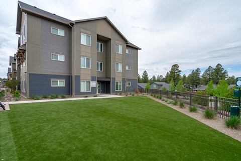 A large grassy area in front of a grey apartment building.