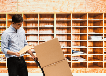 young man holding a book and moving a box in a room