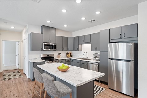 A modern kitchen with a marble countertop and stainless steel appliances.