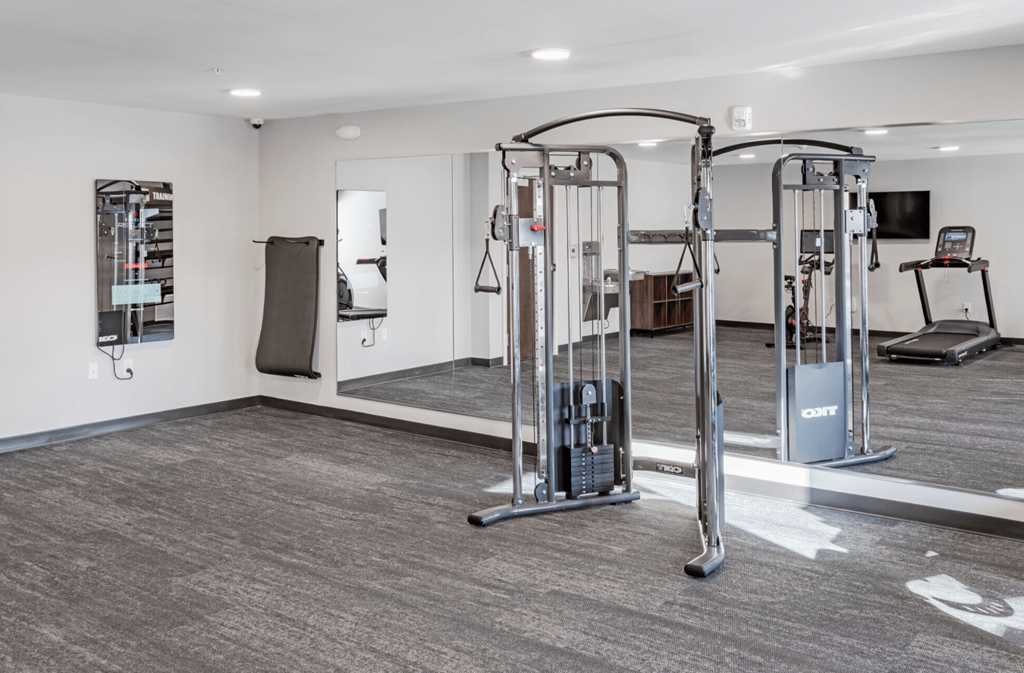 a gym with cardio equipment and a mirror in the corner of a room