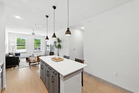 A kitchen with a white counter and a black couch.