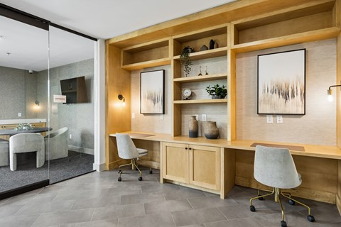 A modern office with a glass wall and a wooden shelf.