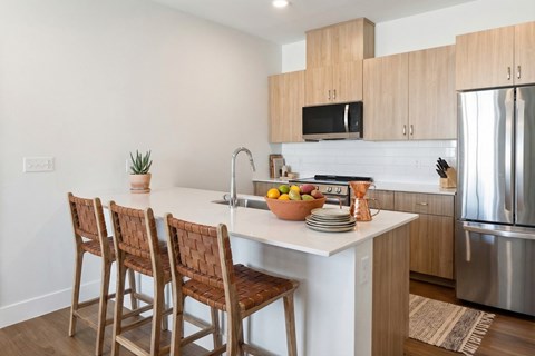 A kitchen with a white countertop and wooden chairs.