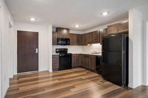 A kitchen with a black refrigerator and wooden cabinets.