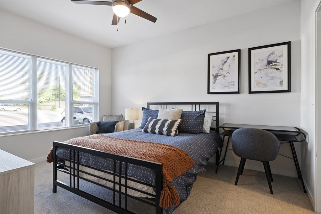 a bedroom with a bed and a desk and a ceiling fan