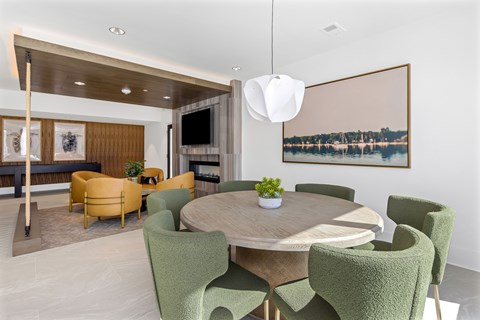 A modern dining room with a round table and green chairs.