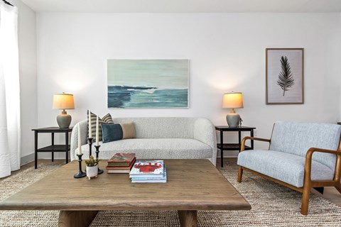 A living room with a couch, two chairs, a coffee table, and a painting on the wall.