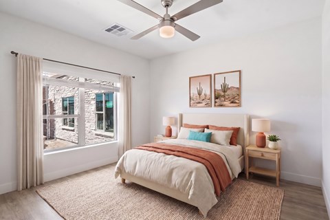 A bedroom with a bed, a ceiling fan, and a window with curtains.