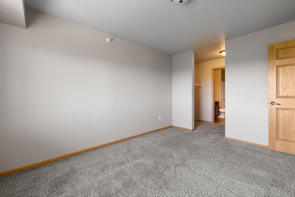 a bedroom with grey carpet and a wooden door