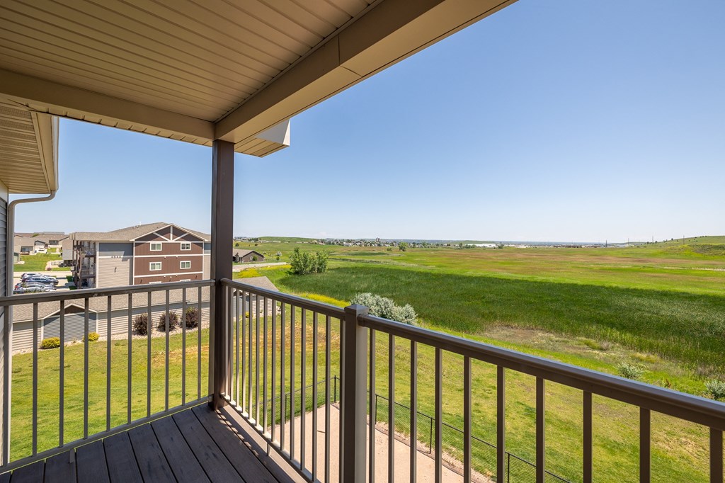 a view from the deck of a house with a green field in the background