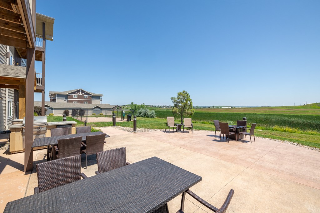 a patio with tables and chairs and a house in the background
