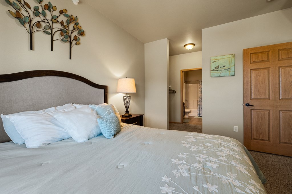 a bedroom with a large bed and a bathroom in the background