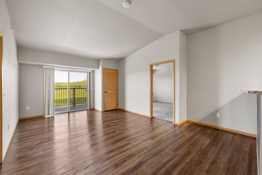 a bedroom with hardwood floors and a sliding glass door to a balcony