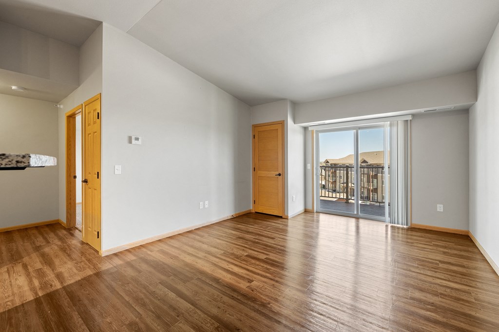 a bedroom with hardwood floors and a balcony