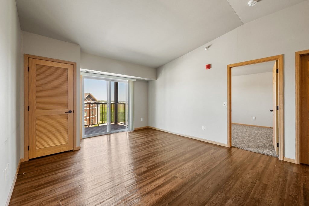 a bedroom with hardwood floors and a sliding glass door leading to a balcony