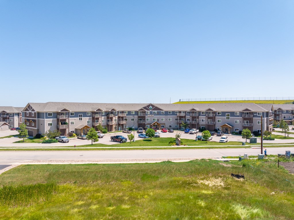 an apartment complex with green grass in the foreground and a blue sky in the background