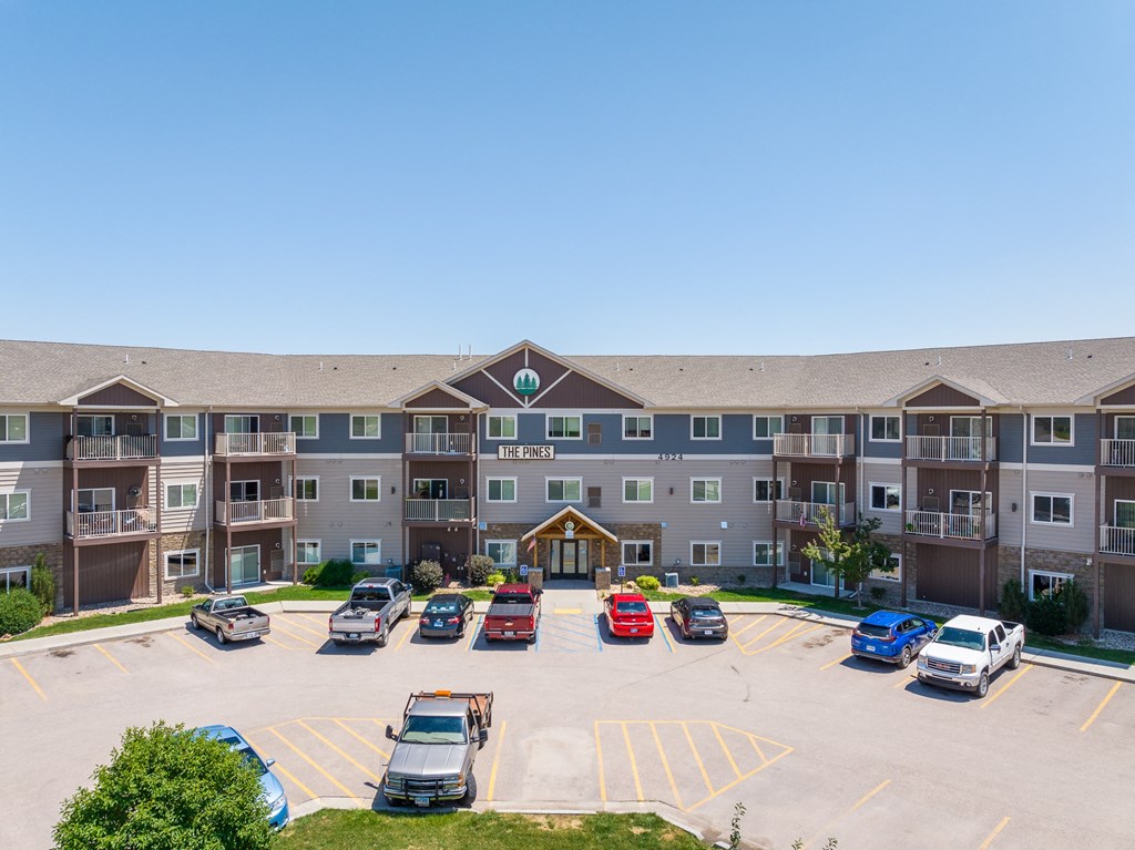 a large parking lot with cars in front of an apartment complex