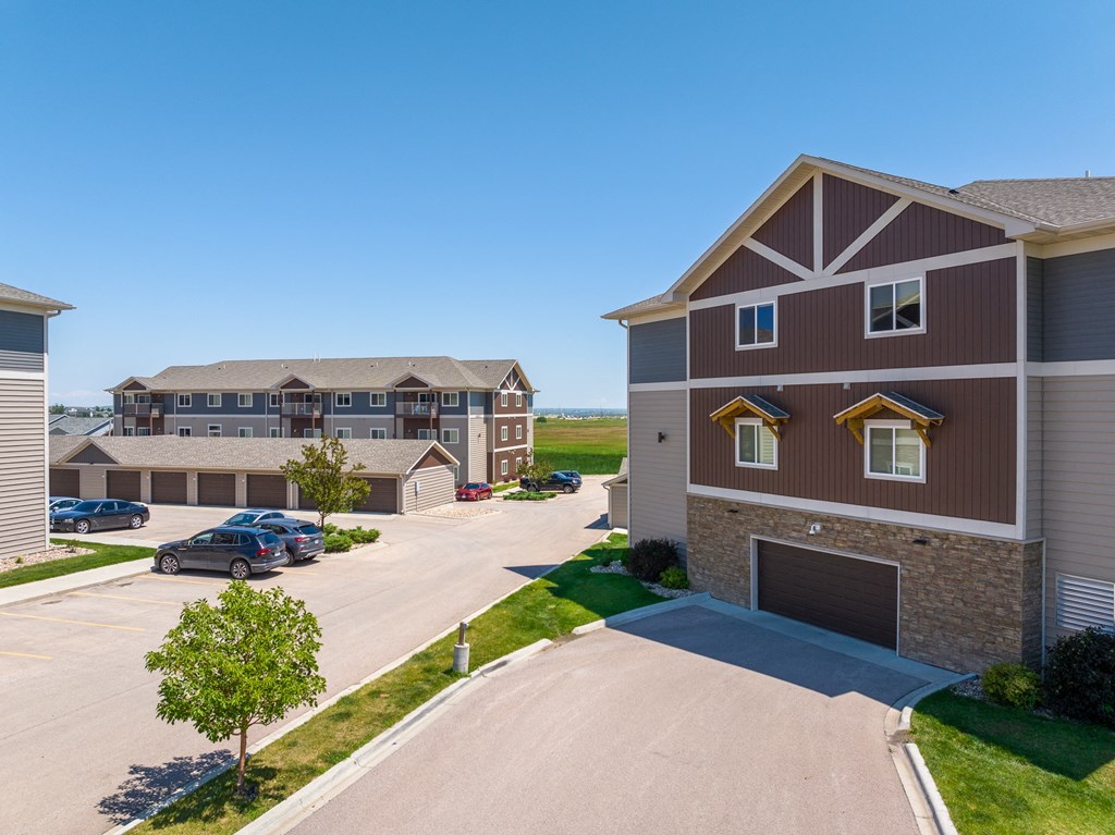a large apartment complex with a parking lot and grassy field in the background