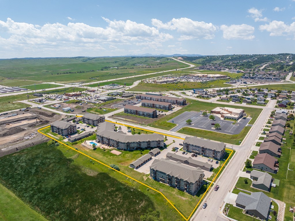 an aerial view of a city with several buildings and a green field in the background