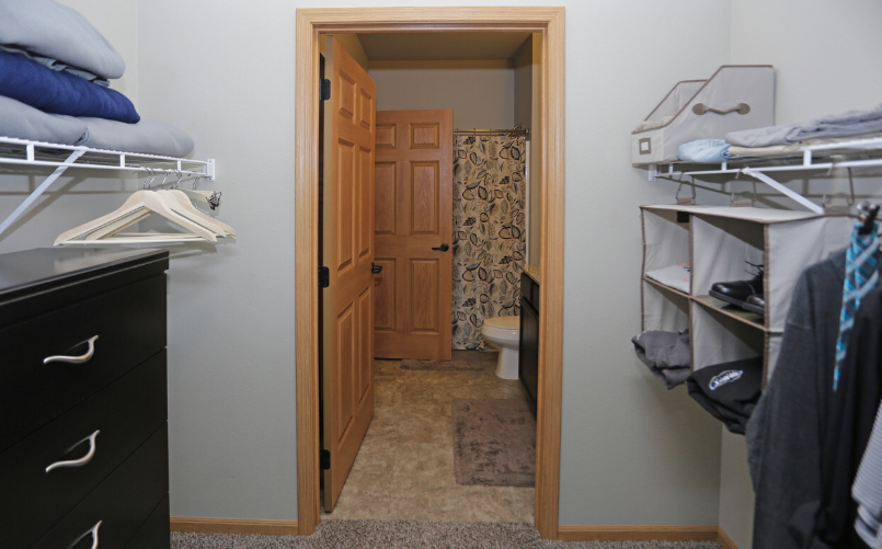 a walk in closet in a small room with a door to the bathroom