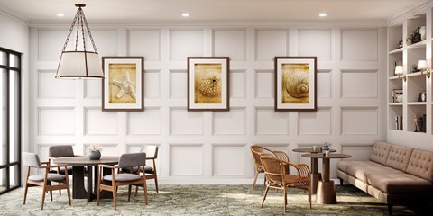 A living room with a grey sofa, a wooden table and chairs, and three framed pictures on the wall.
