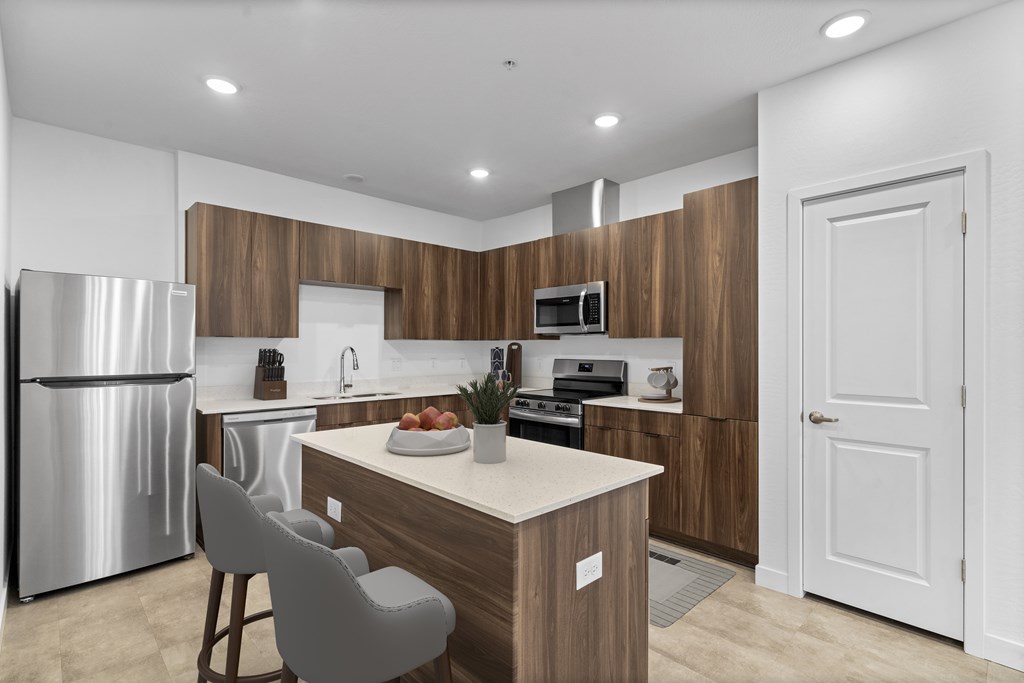 A modern kitchen with a refrigerator, sink, and a dining table with chairs.