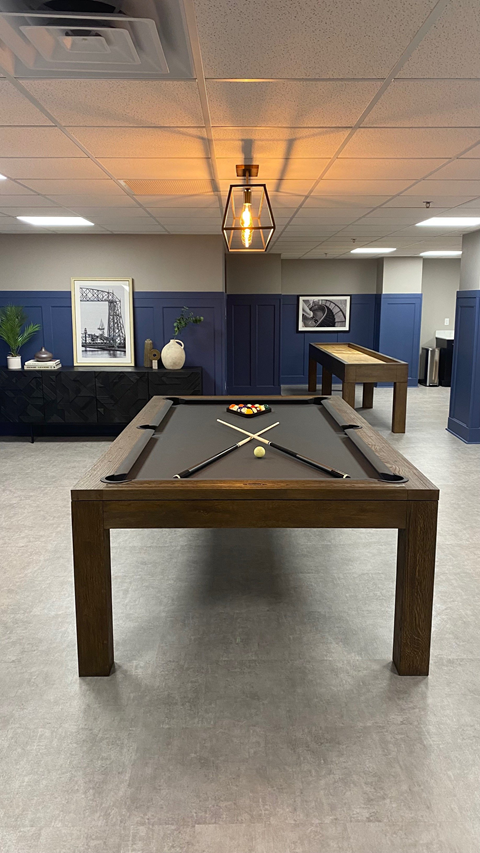 A pool table in a room with a light hanging from the ceiling.