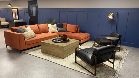 A living room with a blue wall and a large orange sofa.