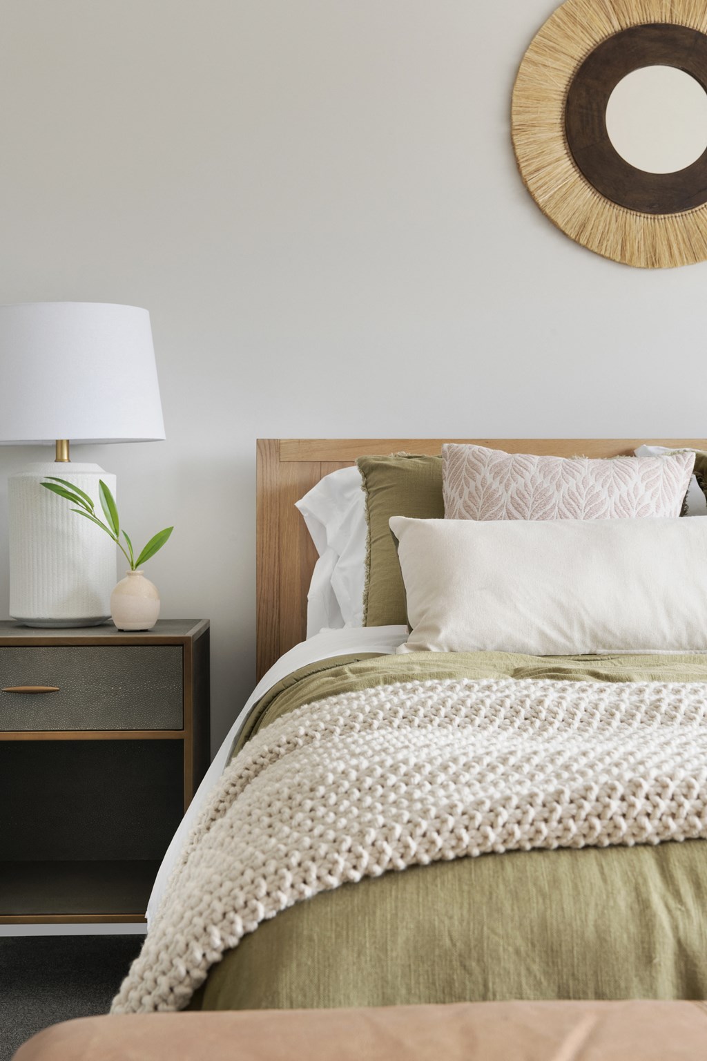 a bedroom with a bed and a nightstand with a lamp and a mirror