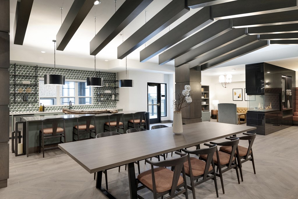 a long dining table in a room with a kitchen and a bar