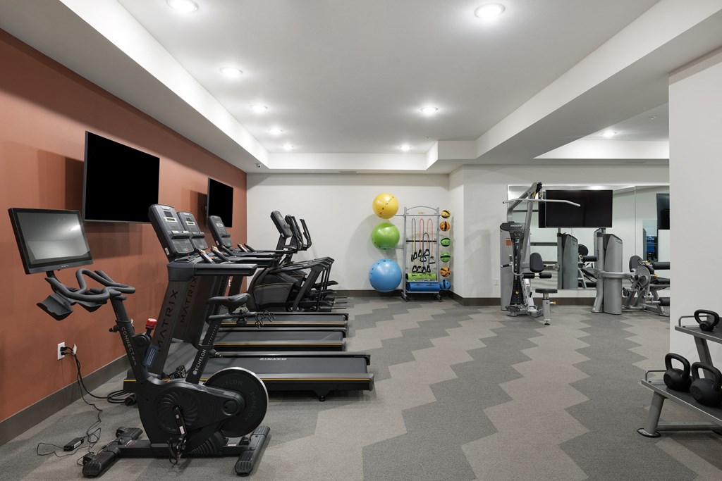 a gym with treadmills and weights and a tv