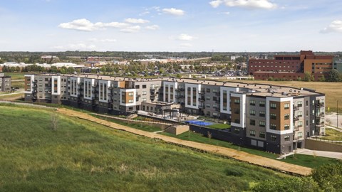 A row of modern apartment buildings are lined up on a grassy hill.