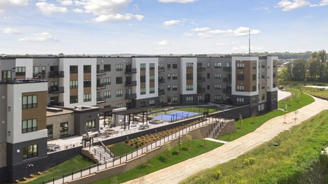 Apartment complex with a pool and green grassy area.