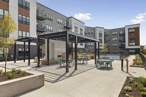 A sunny day at a modern apartment complex with a pool and outdoor seating area.