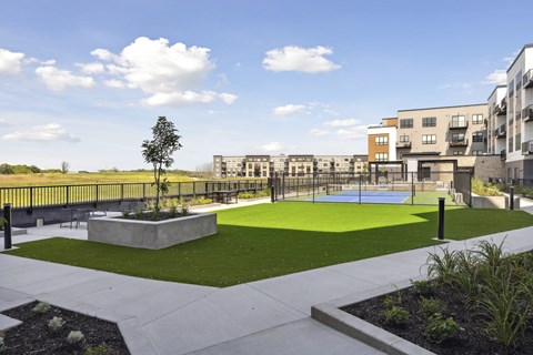 A park area with a tree, benches and a playground.