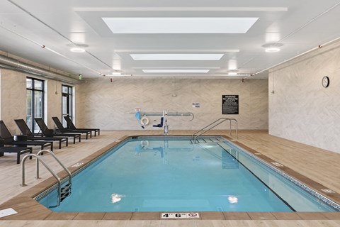 A large indoor swimming pool with a glass bottom and a diving board.