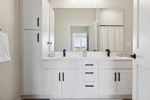 A white bathroom with a large mirror and a window.