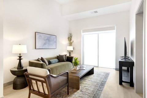 A living room with a sofa, a chair, a table, and a painting on the wall.
