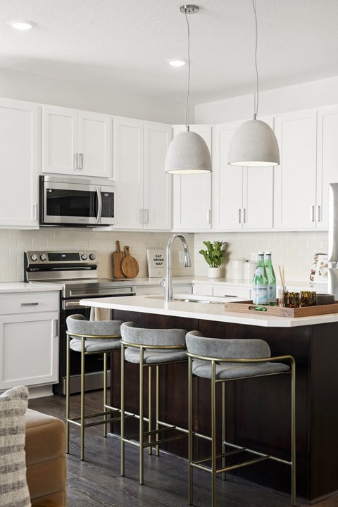 a kitchen with white cabinets and a bar with three stools