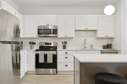 A modern kitchen with white cabinets and stainless steel appliances.